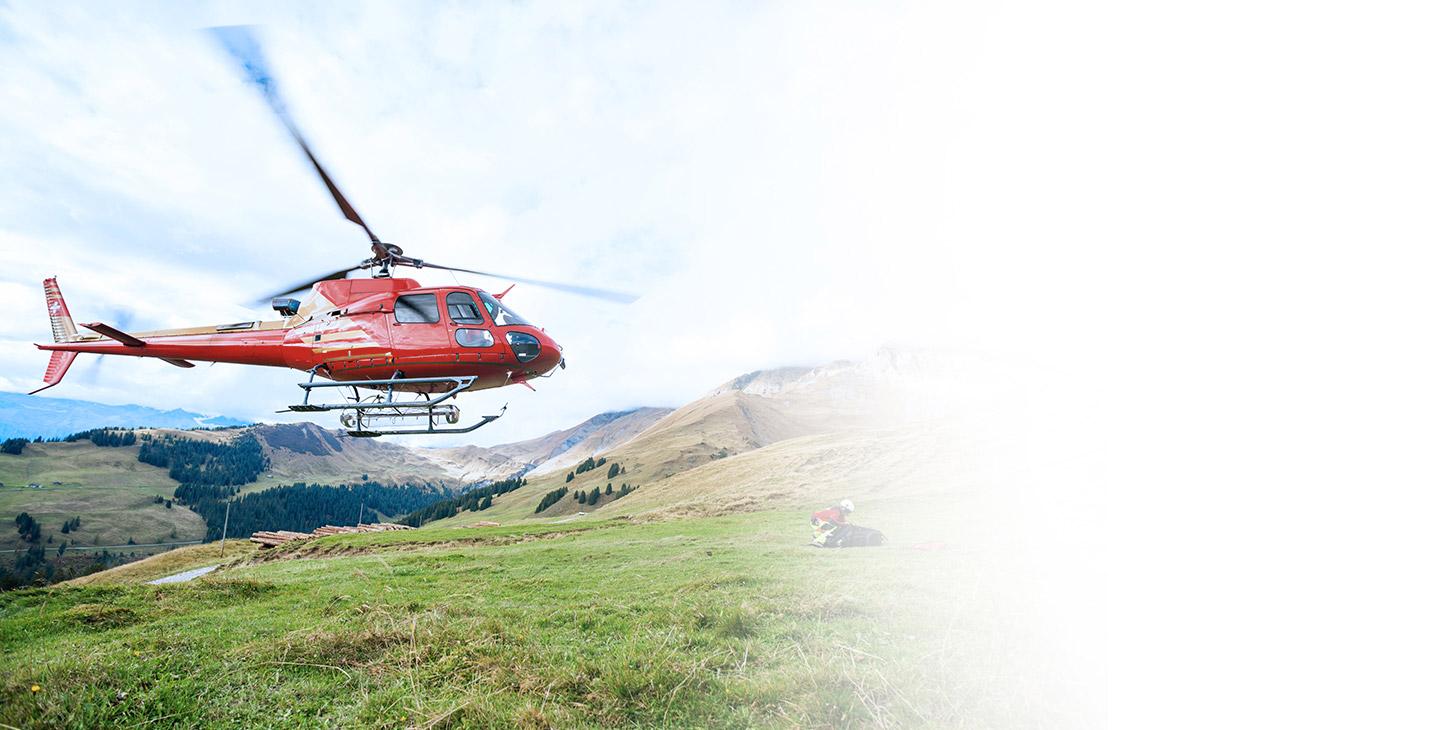 一架红色的直升机飞过一名跪在山边草地上的男子