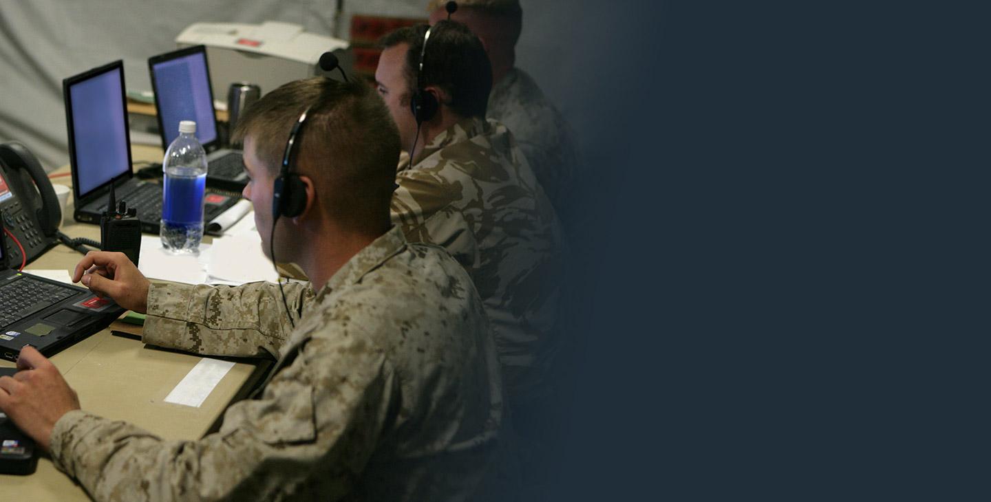 三名男性战士在战术行动中心看着一台笔记本电脑
