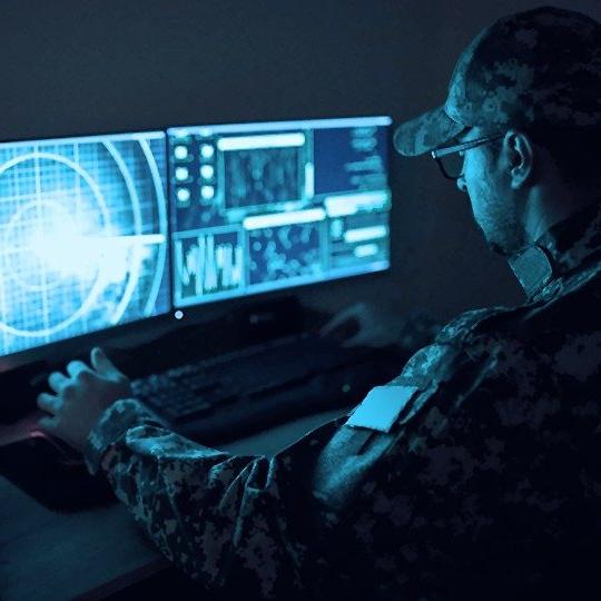 身穿绿色军装的男子坐在一台受政府网络安全系统保护的电脑前